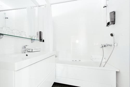 a white bathroom with a sink and a bath tub at Yyteri Spa Hotel in Pori