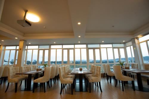 a restaurant with tables and chairs and windows at Dragon King 1 Hotel in Da Lat