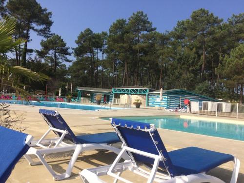 2 chaises assises en face d'une piscine dans l'établissement Mobilhome Landes Les Dunes de Contis, à Saint-Julien-en-Born