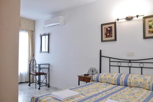 a bedroom with a bed and a desk and a chair at Hostal Almanzor in Córdoba