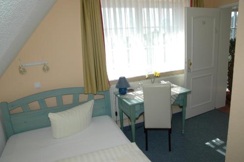 a bedroom with a bed and a table and a window at Landhotel Ostseetraum & Fewo in Warnemünde