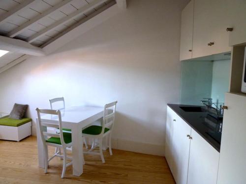 a kitchen with a white table and chairs in a room at Guimarães Studios Lounge in Guimarães