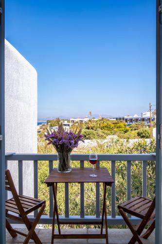 a table with a glass of wine and flowers on a balcony at Secret Garden Apartments in Mýkonos City