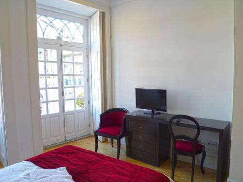 a bedroom with a bed and a desk and two chairs at Guimarães Studios Lounge in Guimarães