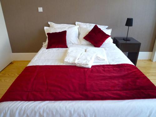 a red and white bed with red pillows on it at Guimarães Studios Lounge in Guimarães