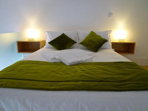 a large bed with green and white sheets and pillows at Guimarães Studios Lounge in Guimarães