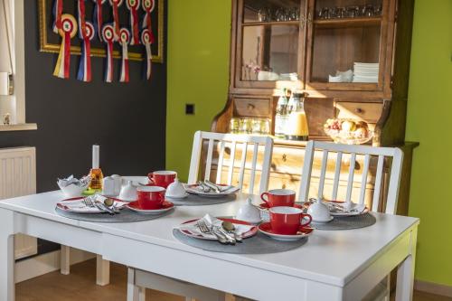 a white table with red cups and saucers on it at kleinHOTEL Steinau-Rabenstein GbR in Steinau an der Straße