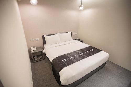 桃園區的住宿－太客旅店，一间卧室配有一张带白色床单的大床