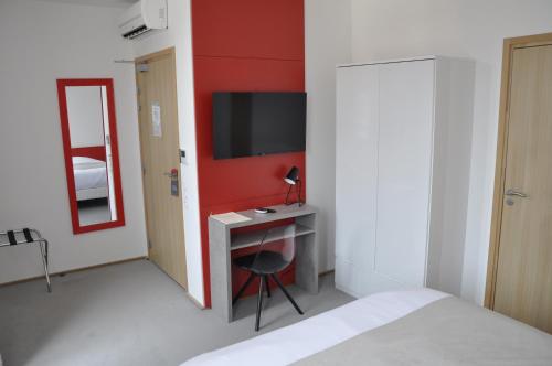 a bedroom with a bed and a desk with a television at Les Tonnelles in Bar-sur-Seine