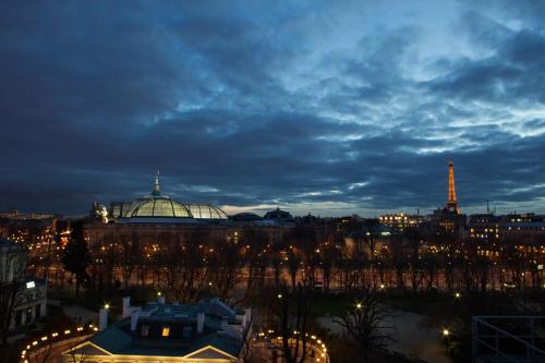 a view of a city at night with the eiffel tower at La Réserve Paris Hotel & Spa in Paris