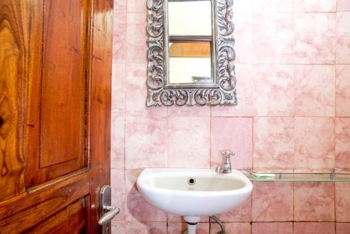 La salle de bains est pourvue d'un lavabo et d'un miroir mural. dans l'établissement Shindu Home Stay, à Ubud