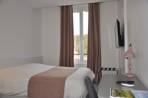 a hotel room with a bed and a desk and a window at Les Tonnelles in Bar-sur-Seine