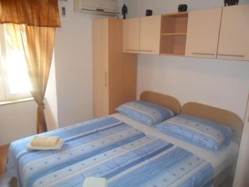 a bedroom with a bed with blue sheets and a window at Guest House Leon in Korčula