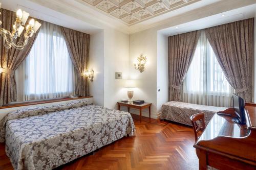 a bedroom with two beds and a desk and windows at Hotel Aventino in Rome
