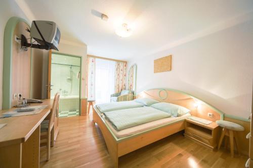 a bedroom with a bed and a desk and a sink at Hotel zum Kirchenwirt Mariazell in Mariazell