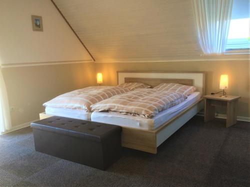 ein Schlafzimmer mit einem großen Bett mit einer Bank daneben in der Unterkunft Huus Störtebeker in Dornumersiel