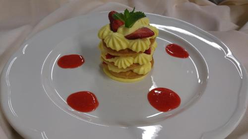 a white plate with a dessert with strawberries on it at Alpen Garten Hotel Margherita in Rumo