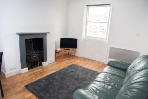 a living room with a leather couch and a fireplace at Quire Court Apartment in Gloucester