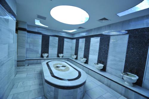 Grand Cenas Hotel في أغري: حمام به ثلاث دورات مياه وحوض استحمام
