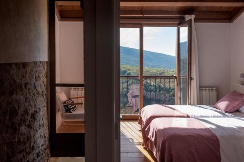 a bedroom with a bed and a balcony with a view at Casa Jou in Abella de la Conca