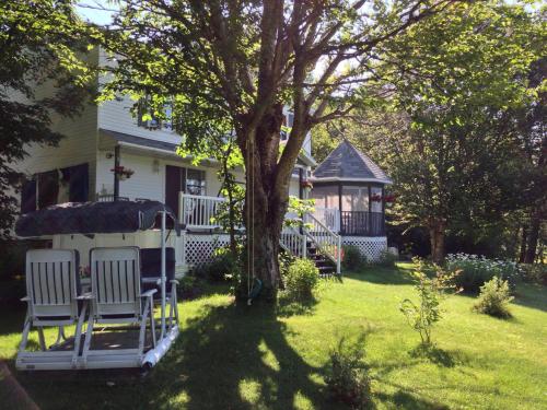 a yard with chairs and a tree and a house at Le Reflet de la Rivière B&B in Weedon-Centre