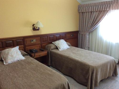 a hotel room with two beds and a window at Hotel O Castelo in Cervo