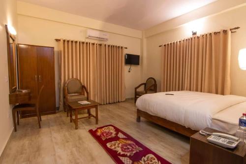 Habitación de hotel con cama, escritorio y silla en Hotel Basanta Inn, en Pokhara