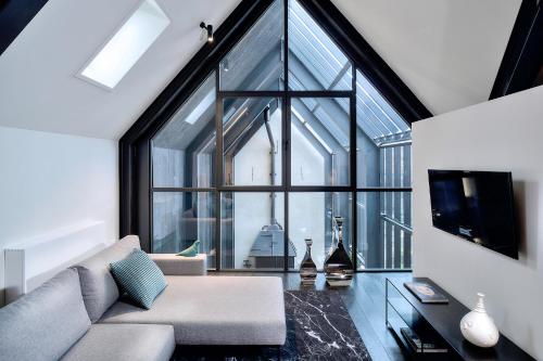 a living room with a couch and a large window at Kazerne Hotel - Member of Design Hotels in Eindhoven