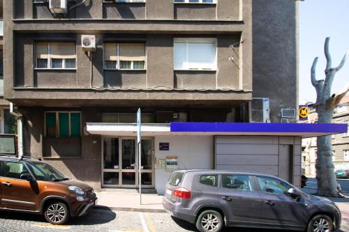 due auto parcheggiate in un parcheggio di fronte a un edificio di Captain's Crib a Belgrado