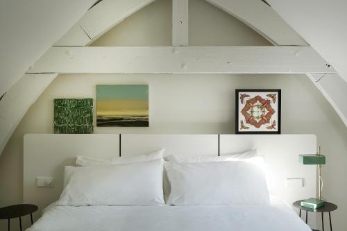 a white bed with white pillows in a bedroom at Kazerne - Member of Design Hotels in Eindhoven