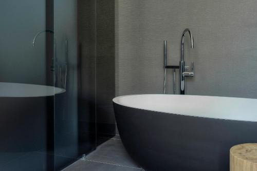 a bathroom with a bath tub and a sink at Kazerne Hotel - Member of Design Hotels in Eindhoven