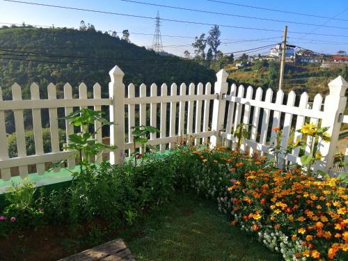 a white picket fence with flowers in a yard at Melford Nuwaraeliya in Nuwara Eliya