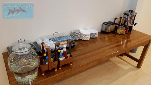 a wooden table with plates and a vase on it at Baramate Khao Lak - SHA PLUS in Khao Lak