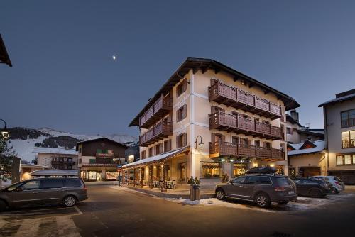 a large building with cars parked in a parking lot at Hotel Compagnoni in Livigno