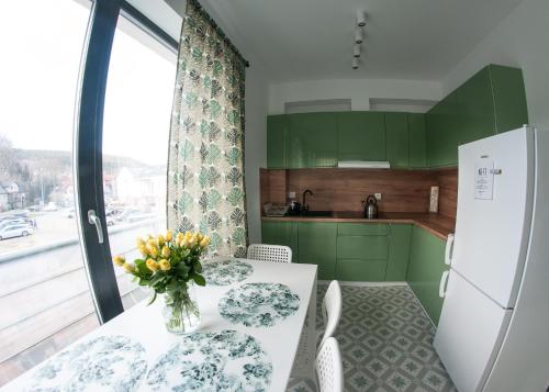 a kitchen with a table with a vase of flowers on it at Zielone Apartamenty in Świeradów-Zdrój