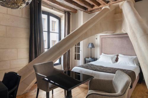 a bedroom with a bed and a table and a chair at Hôtel Le Presbytère in Paris