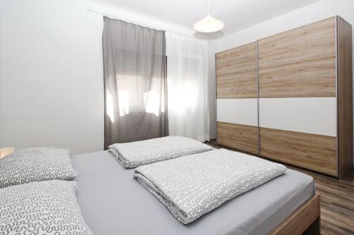 a bedroom with two beds and a wooden cabinet at Apartment Mihaela in Baška
