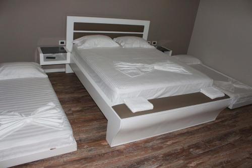 a bedroom with a large white bed with two pillows at Palmanova Beach Mardok in Vlorë