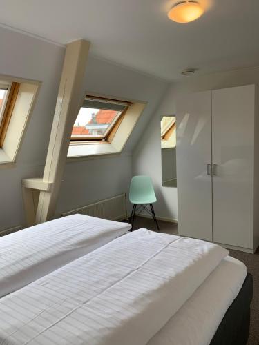 een slaapkamer met een wit bed en 2 ramen bij Stadslogement By Peek in Sneek