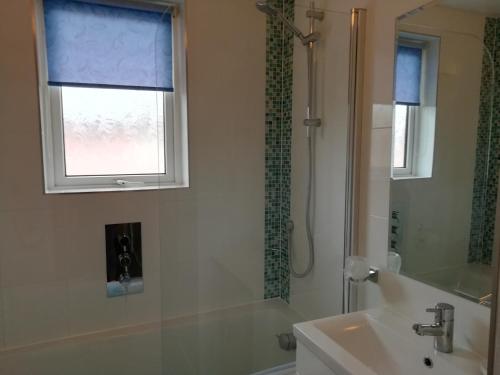 a bathroom with a sink and a shower and a window at 57 New Esplanade Court, Beach Close By Pool View in Paignton