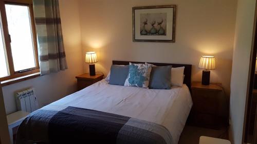 a bedroom with a large bed with two lamps at Birch Lodge in Fort William