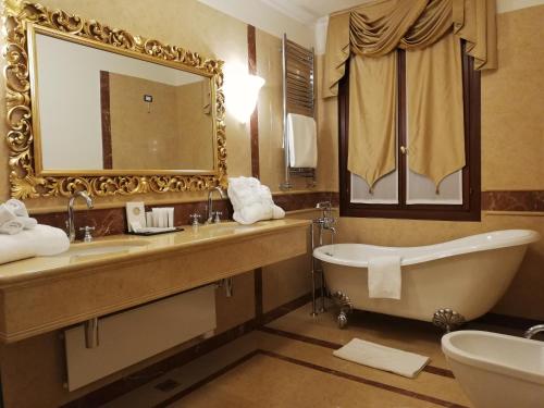 a bathroom with a tub and a sink and a mirror at Ca' Bonfadini Historic Experience in Venice