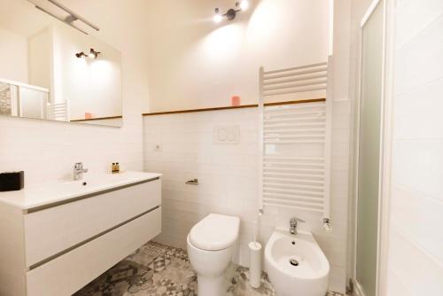 a white bathroom with a toilet and a sink at MADI' casa vacanze in Laiatico