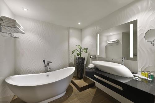 een badkamer met een groot wit bad en een grote spiegel bij Park Mall Hotel & Conference Center in Sétif