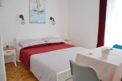 a bedroom with a white bed with a red blanket at Apartments Mike in Novalja