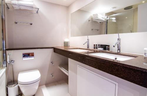 a bathroom with two sinks and a toilet and a mirror at Blakemore Hyde Park in London