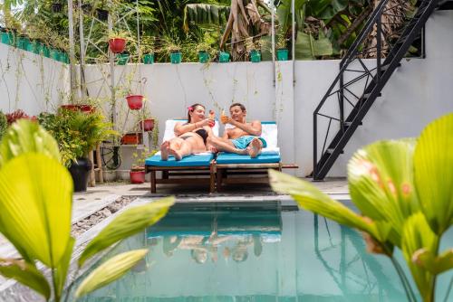 two people laying on a bed next to a swimming pool at Sunny Riverside Homestay in Hoi An