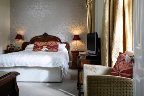 a bedroom with a bed with a teddy bear on it at Elm Grove Country House in Tenby