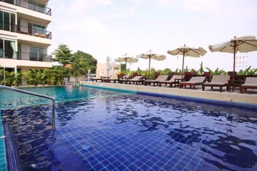 a swimming pool in a hotel with chairs and umbrellas at Diamond Suite in Pattaya South