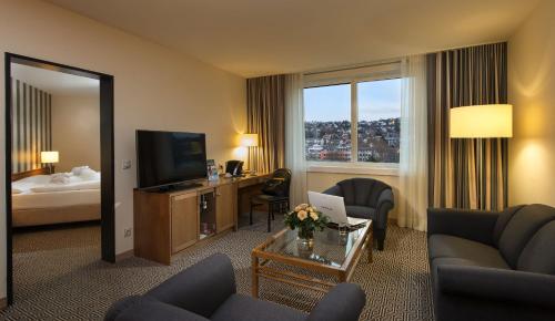 a living room filled with furniture and a tv at Maritim Hotel Stuttgart in Stuttgart